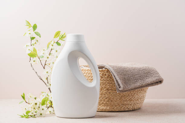 Laundry bottle next to wicker basket filled with towels, surrounded by blooming branches, illustrating wash day.