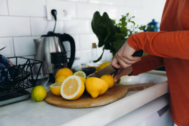 A person slicing lemons on a cutting board in a kitchen, emphasizing eco-friendly cleaning with lemons.