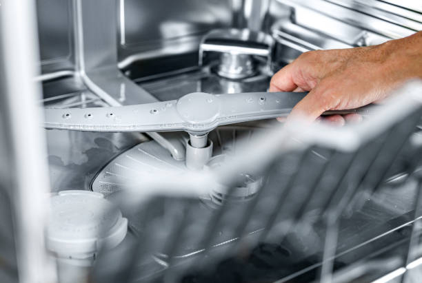 Hand removing dishwasher filter for cleaning to ensure sparkling dishes.
